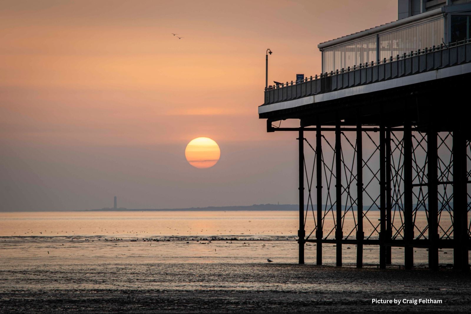 A large yellow sun going down behind the Grand Pier at Weston-super-Mare